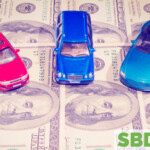 three toy cars sitting on sheet of hundred dollar bills