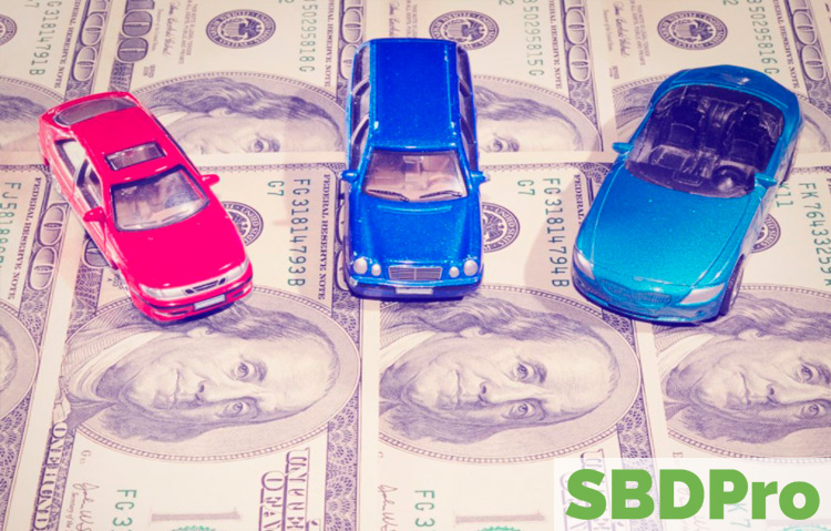 three toy cars sitting on sheet of hundred dollar bills