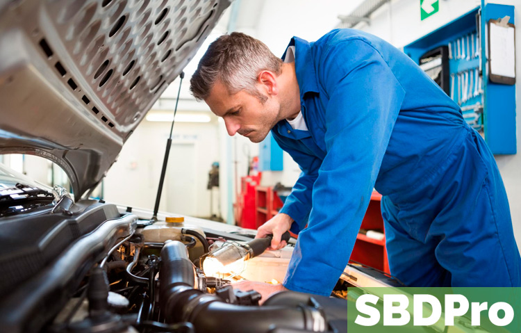 mechanic looking under hood of car