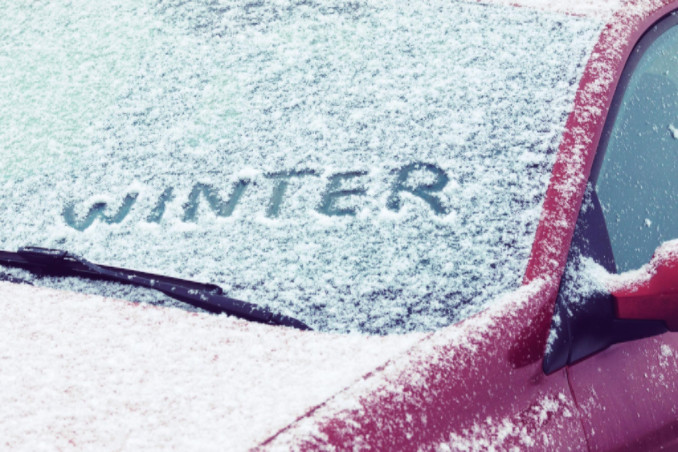 the word winter written on windshield in snow
