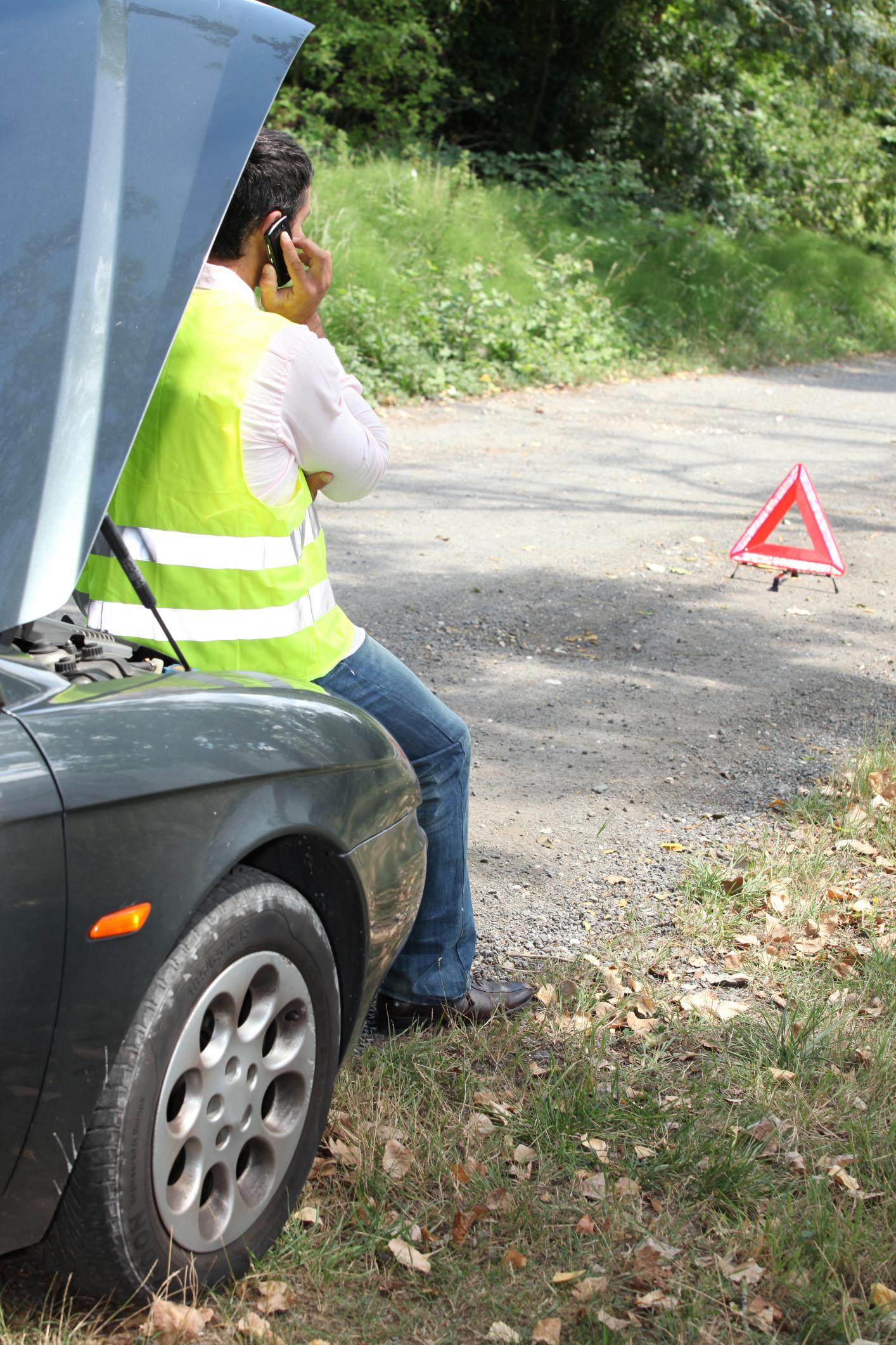 man calling for assistance with his car broken